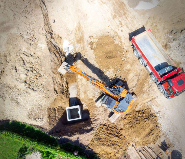 Photographie vue drone d'un suivi de chantier pendant les travaux avec un camion et une pelleteuse